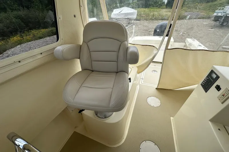 Slide: The Image of Captain's chair inside 2013 Eastern Explorer 248 boat, featuring beige interior and control panel. - 11