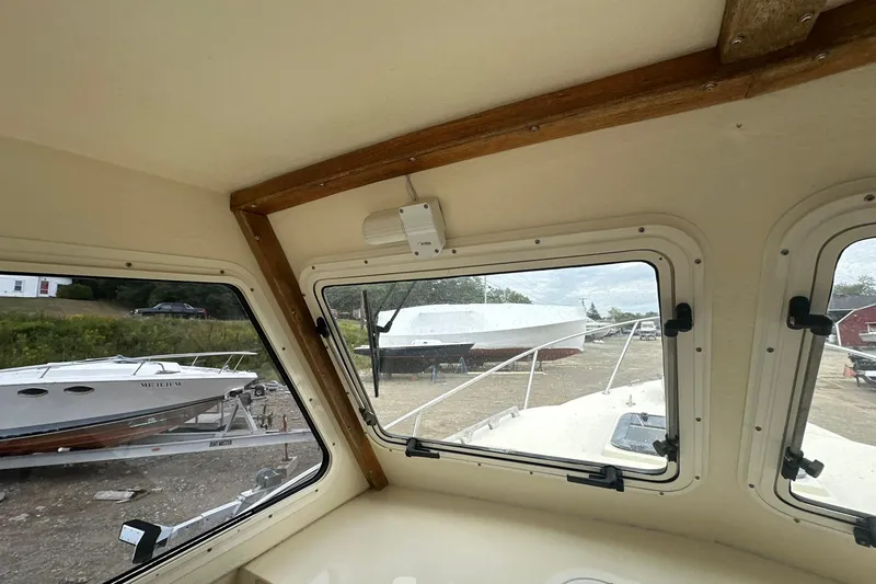 Slide: The Image of Interior view from a 2013 Eastern Explorer 248 boat, showing windows and docked boats outside. - 14