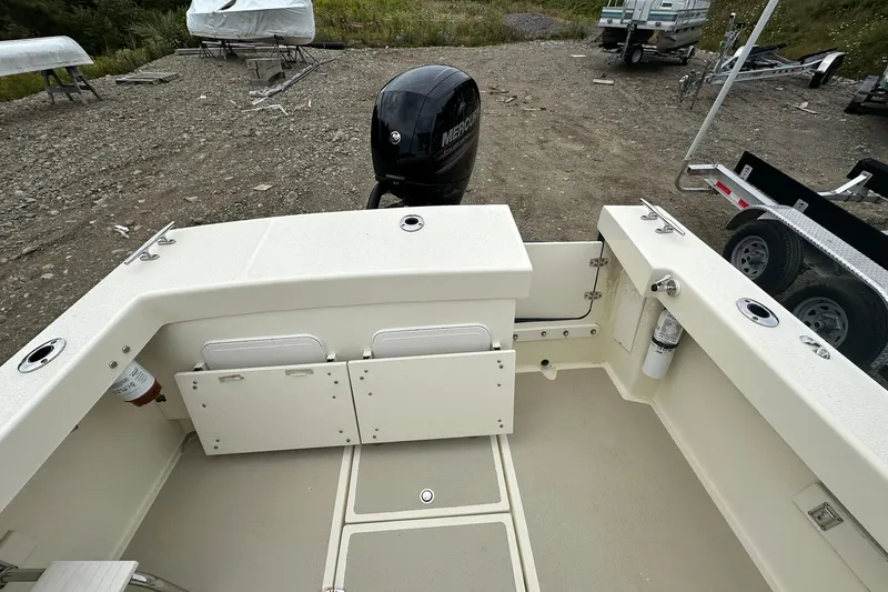 Slide: The Image of 2013 Eastern Explorer 248 boat interior with Mercury outboard motor, parked on gravel. - 21