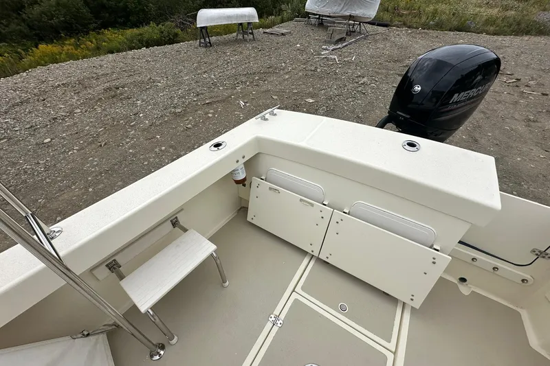 Slide: The Image of 2013 Eastern Explorer 248 boat interior with Mercury outboard motor, docked on gravel. - 22