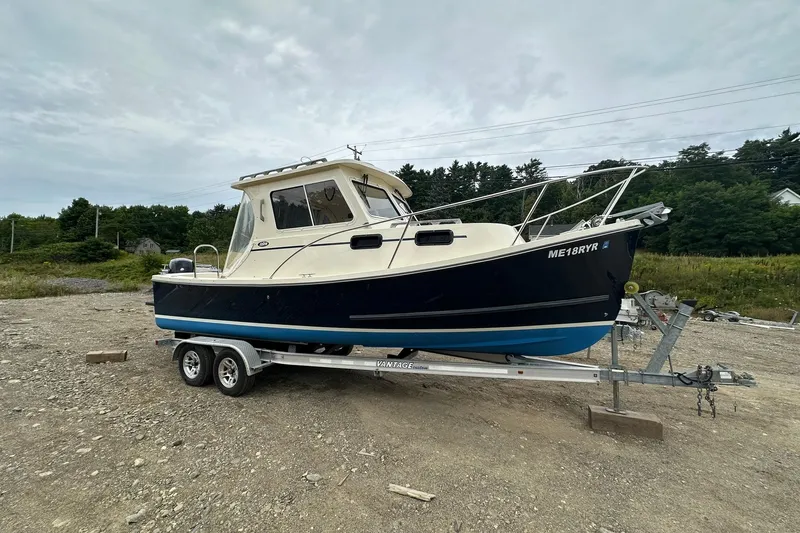 Slide: The Image of 2013 Eastern Explorer 248 boat on trailer, parked on gravel with trees in background. - 3