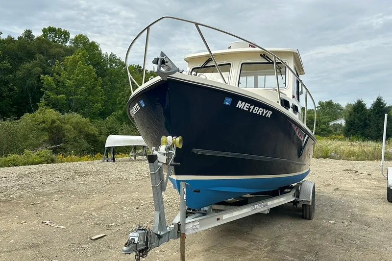 Slide: The Image of 2013 Eastern Explorer 248 boat on trailer, parked outdoors with trees in background. - 4