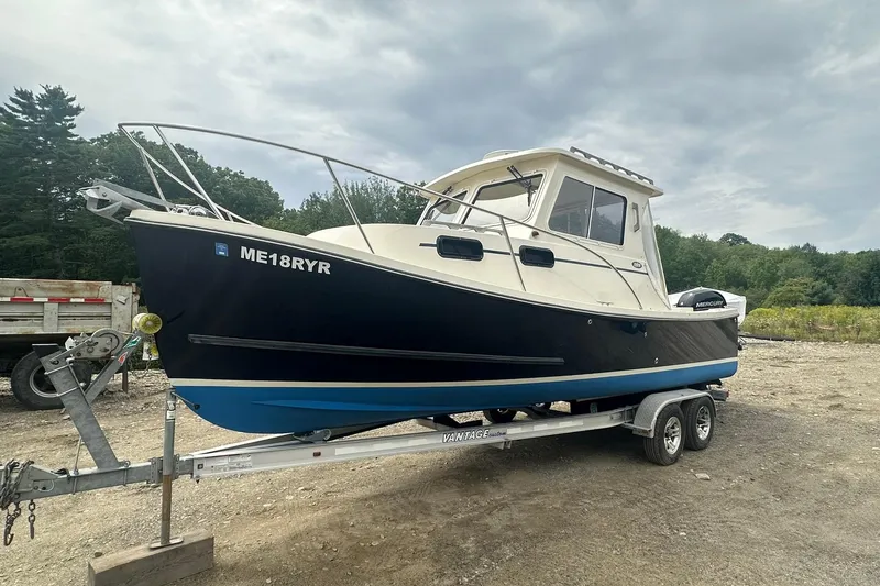 Slide: The Image of 2013 Eastern Explorer 248 boat on trailer, parked outdoors under cloudy sky. - 5
