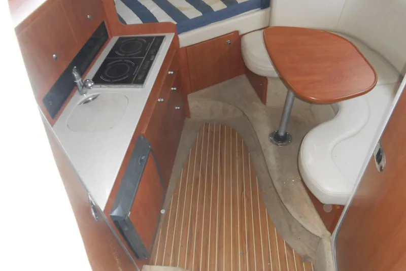 Slide: The Image of 2008 Bayliner 300 interior with kitchenette, seating, and wooden flooring. - 13