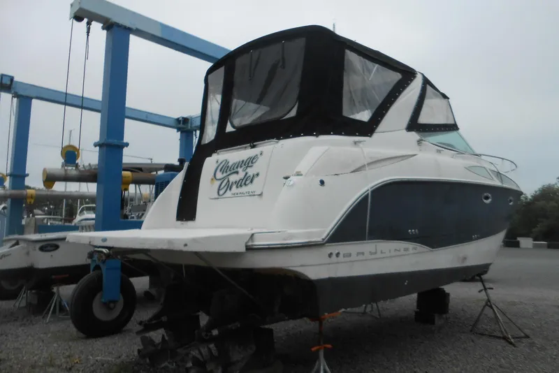 Slide: The Image of 2008 Bayliner 300 boat on dry dock with black canopy and "Change Order" sign. - 2
