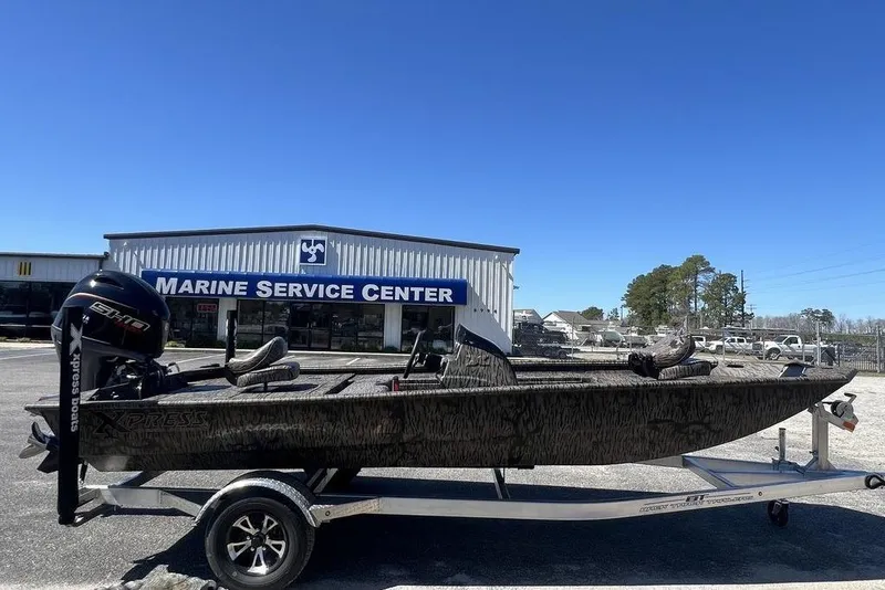 Slide: The Image of 2025 Xpress XP180 boat on trailer at Marine Service Center under clear blue sky. - 8