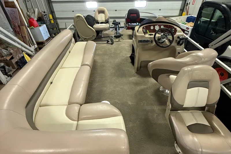 Slide: The Image of 2014 Sun Tracker Fishin' Barge 20 DLX interior with beige seating and steering console. - 14