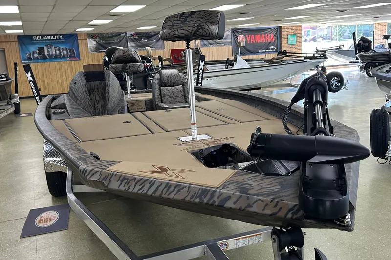 Slide: The Image of 2026 Xpress H20 Bass boat in showroom, featuring camo design and advanced fishing equipment. - 1