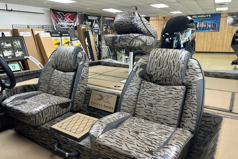 Slide: The Image of 2026 Xpress H20 Bass boat interior with camo seats and Yamaha engine in showroom. - 4