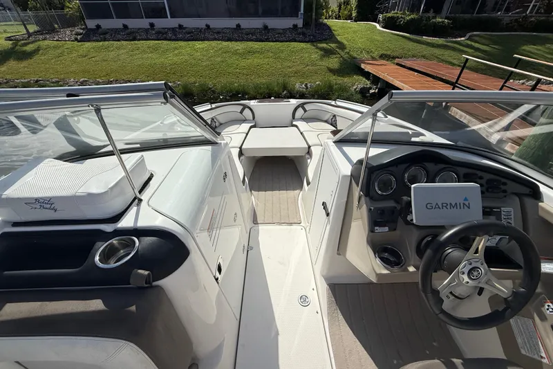 Slide: The Image of 2014 Yamaha Boats 242 Limited S interior with Garmin navigation system, docked by grassy area. - 19