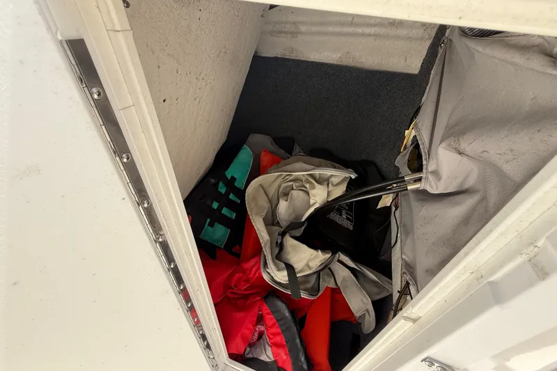 Slide: The Image of Storage compartment in a 2014 Yamaha Boats 242 Limited S, containing life jackets and gear. - 25