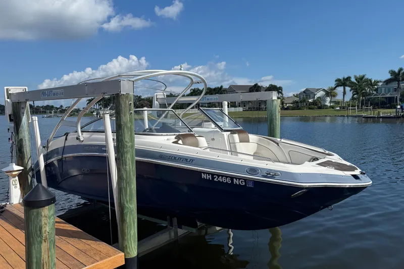 Slide: The Image of 2014 Yamaha Boats 242 Limited S on lift, docked by waterfront homes. - 3