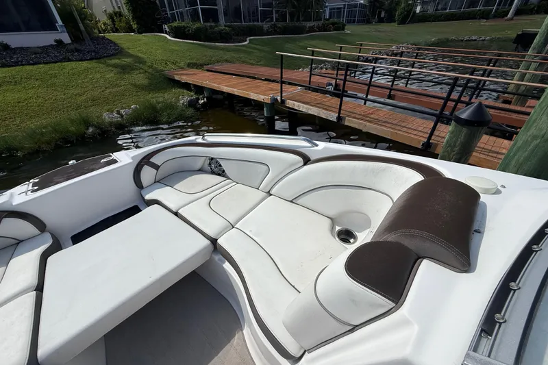 Slide: The Image of 2014 Yamaha Boats 242 Limited S interior with white and brown seating near a dock. - 30
