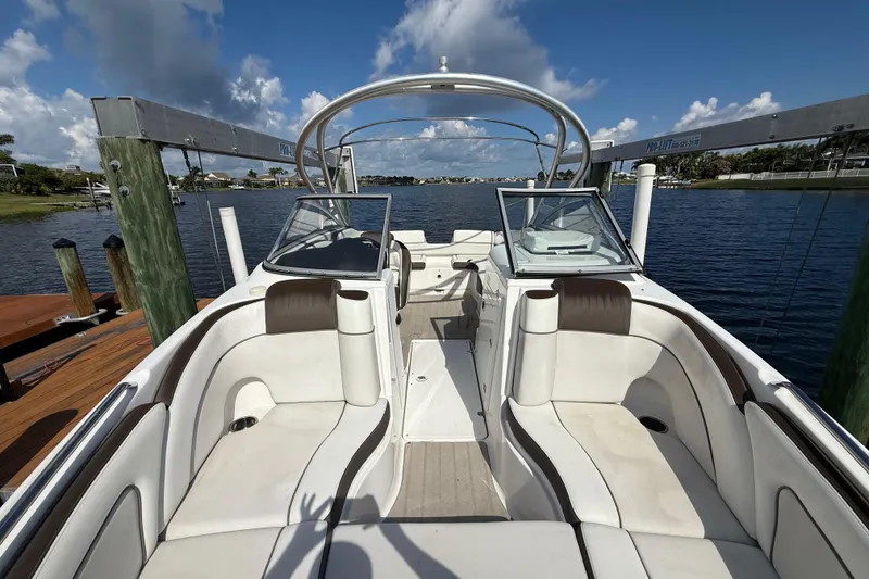 Slide: The Image of 2014 Yamaha Boats 242 Limited S interior with white seating, docked by a serene lake. - 37