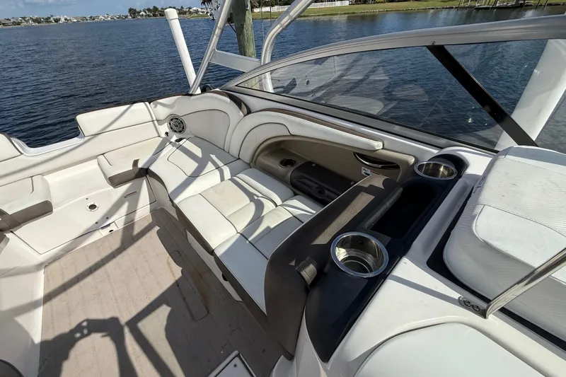 Slide: The Image of 2014 Yamaha Boats 242 Limited S interior with white seating and cup holders by the water. - 41