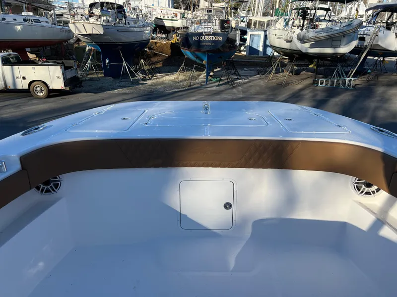 Slide: The Image of 2025 Invincible 33 Catamaran boat interior with brown seating, docked among other boats. - 6