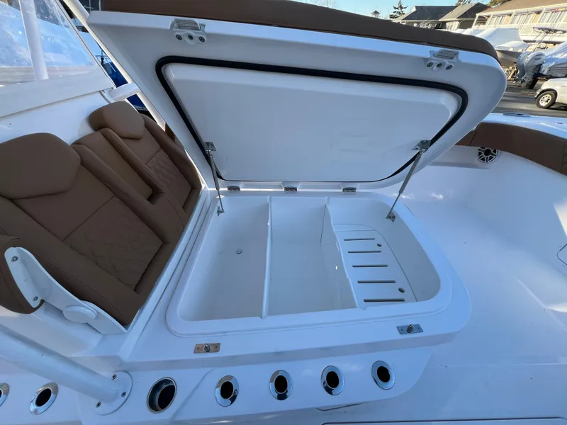 Slide: The Image of 2025 Invincible 33 Catamaran with open storage compartment and brown seating. - 8