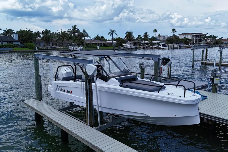 The Image of 2023 Axopar 25 Cross Top boat docked by waterfront homes under cloudy sky. - 0