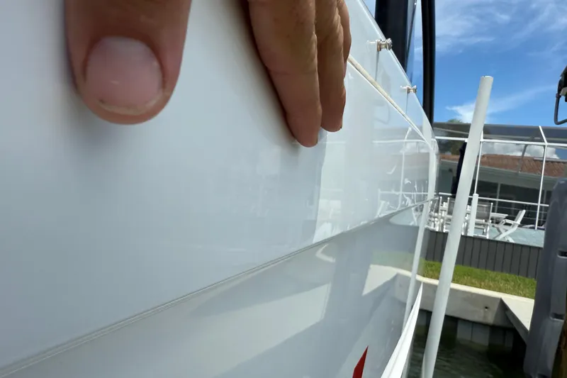 Slide: The Image of Hand touching the sleek exterior of a 2023 Axopar 25 Cross Top boat. - 11