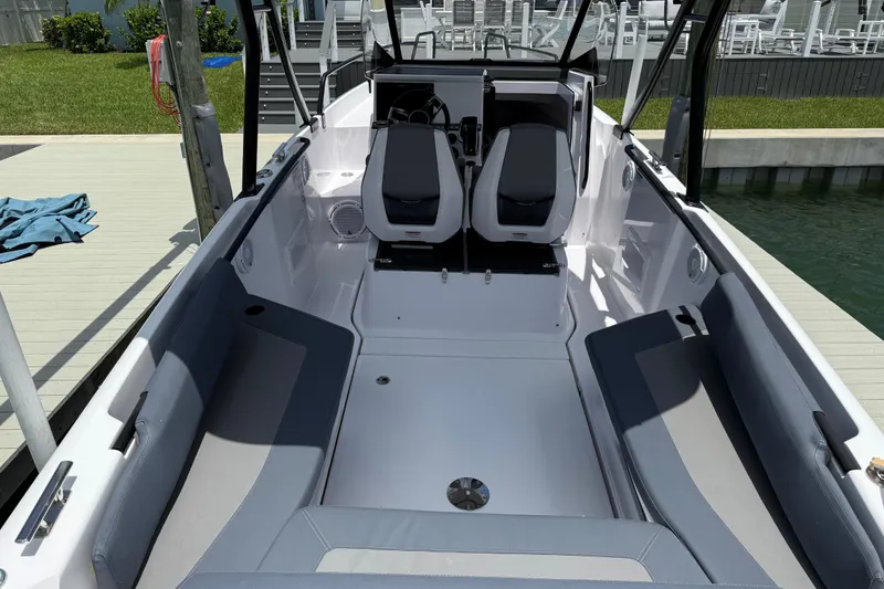 Slide: The Image of 2023 Axopar 25 Cross Top boat interior with seating and helm, docked by water. - 14