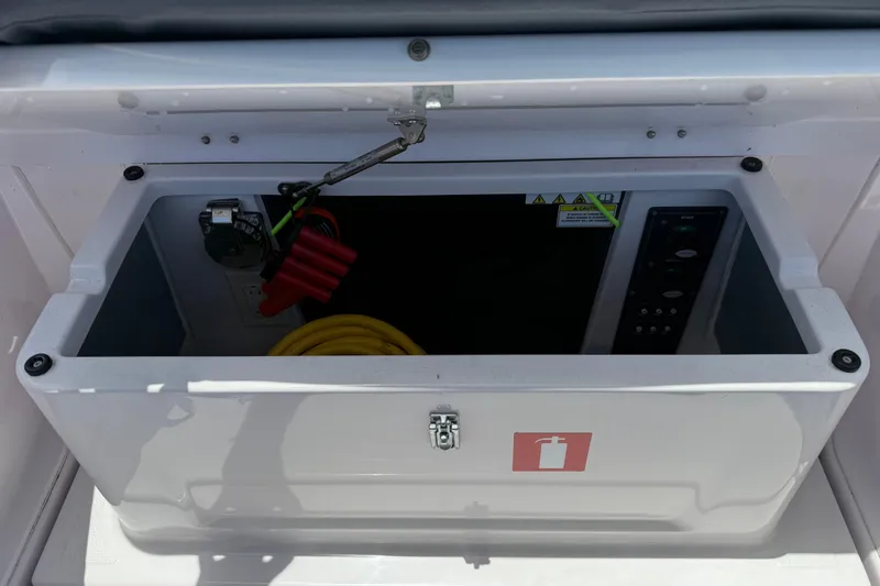 Slide: The Image of Storage compartment on 2023 Axopar 25 Cross Top boat with cables and controls. - 20