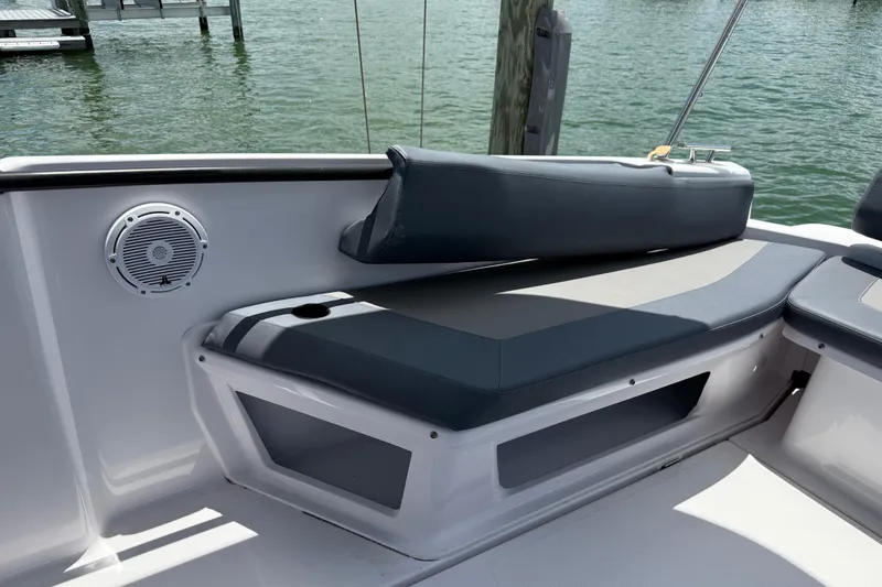 Slide: The Image of 2023 Axopar 25 Cross Top boat seating area with speaker, docked by water. - 21