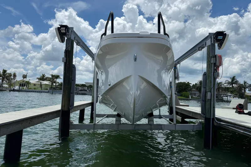 Slide: The Image of 2023 Axopar 25 Cross Top boat on lift, dockside view under cloudy sky. - 3
