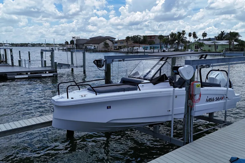 Slide: The Image of 2023 Axopar 25 Cross Top boat docked by waterfront homes under a cloudy sky. - 4