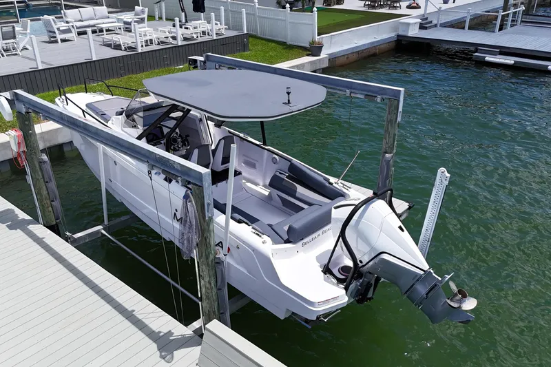 Slide: The Image of 2023 Axopar 25 Cross Top boat docked on a lift by a waterfront deck. - 6