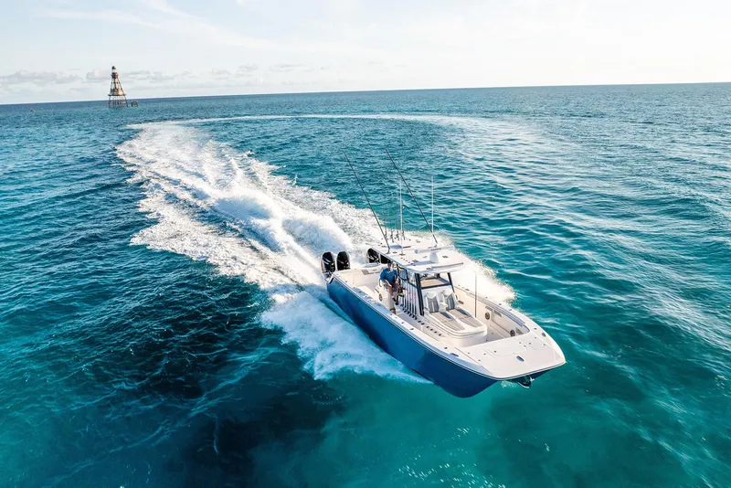 Slide: The Image of 2025 Invincible 36 Catamaran cruising on open ocean, lighthouse in background. - 1