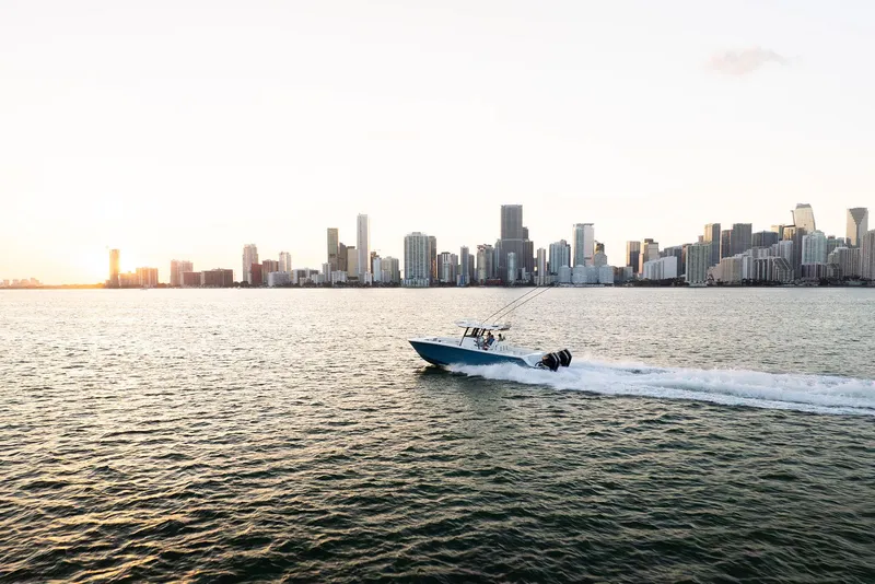 Slide: The Image of 2025 Invincible 36 Catamaran cruising near city skyline at sunset. - 2