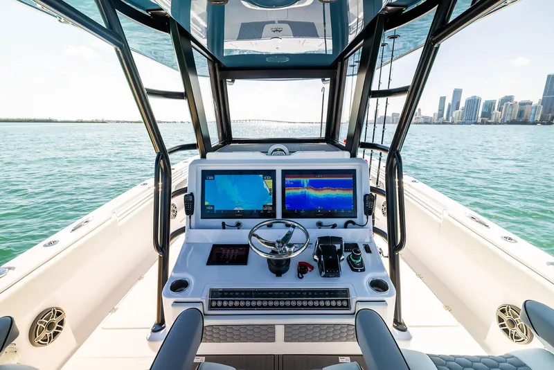 Slide: The Image of 2025 Invincible 36 Catamaran helm with dual screens, steering wheel, and ocean view. - 10