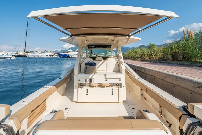 Slide: The Image of 2023 Scout 425 LXF boat interior with helm, luxurious seating, and waterfront view. - 11