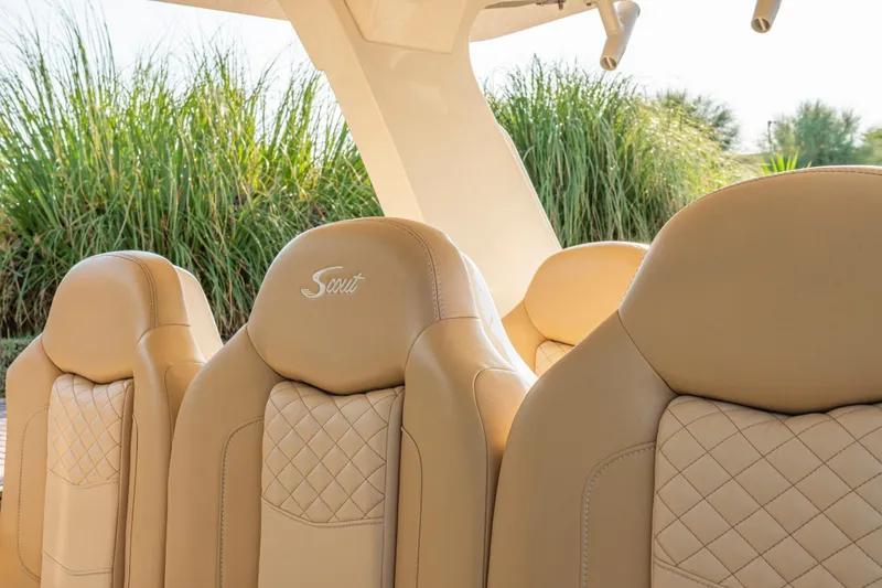 Slide: The Image of 2023 Scout 425 LXF boat interior with luxurious seating, docked near yachts and scenic mountains. - 24