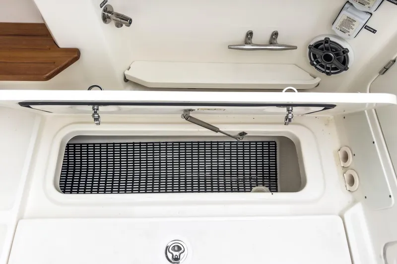 Slide: The Image of 2022 Boston Whaler 350 Realm boat storage compartment with open lid and speaker. - 29