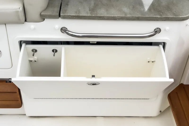 Slide: The Image of 2022 Boston Whaler 350 Realm storage compartment with stainless steel handle and dual sections. - 32