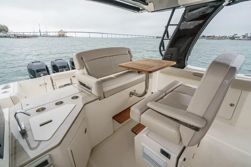 Slide: The Image of 2022 Boston Whaler 350 Realm interior with seating, table, and ocean view. - 54