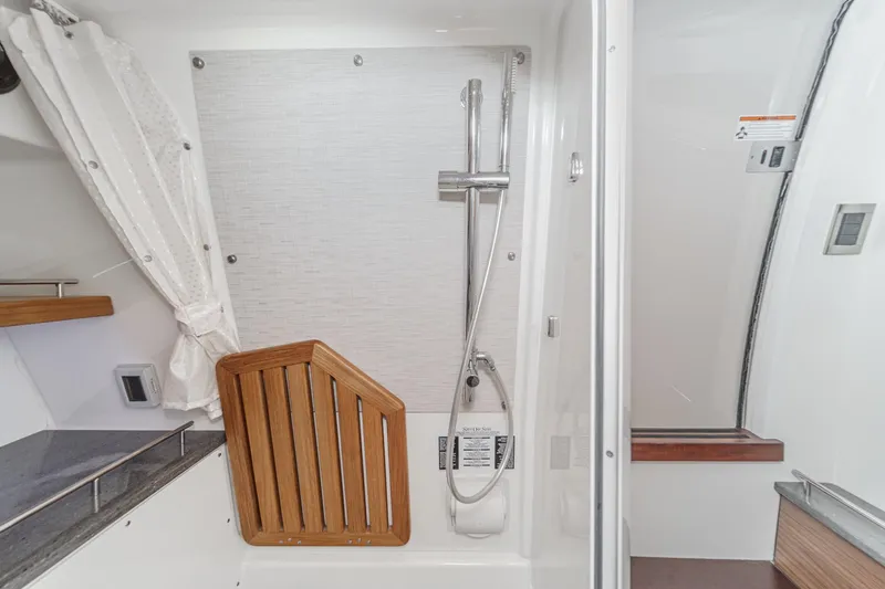 Slide: The Image of 2022 Boston Whaler 350 Realm bathroom with shower and wooden seat. - 66