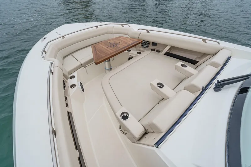 Slide: The Image of 2022 Boston Whaler 350 Realm boat interior with cushioned seating and wooden table. - 67