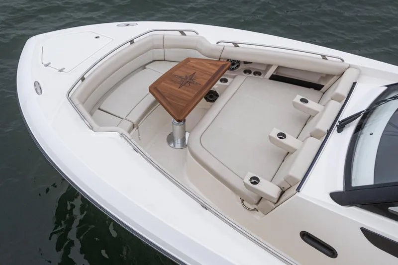 Slide: The Image of 2022 Boston Whaler 350 Realm boat with luxurious seating and wooden table on deck. - 69