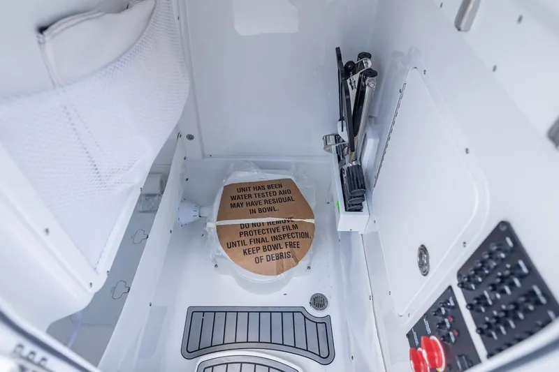 Slide: The Image of 2026 Sea Hunt Gamefish 25 interior with protective film on toilet, clean and organized. - 9