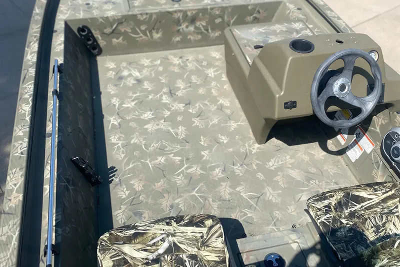 Slide: The Image of 2024 Tracker Grizzly 1754SC boat interior with camouflage design and steering console. - 5