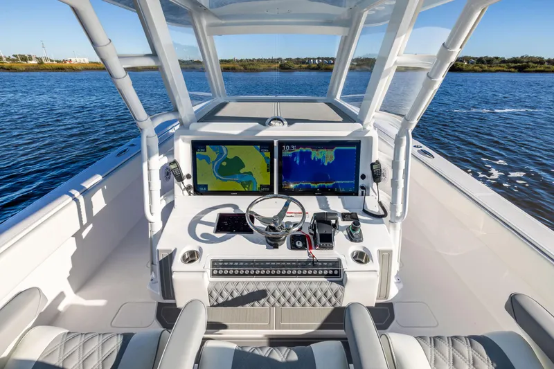 Slide: The Image of 2025 Invincible 38 Catamaran cockpit with advanced navigation systems on a serene water backdrop. - 10