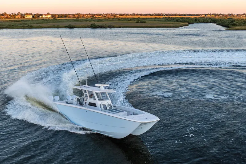 Slide: The Image of 2025 Invincible 38 Catamaran making a sharp turn on a scenic waterway. - 0