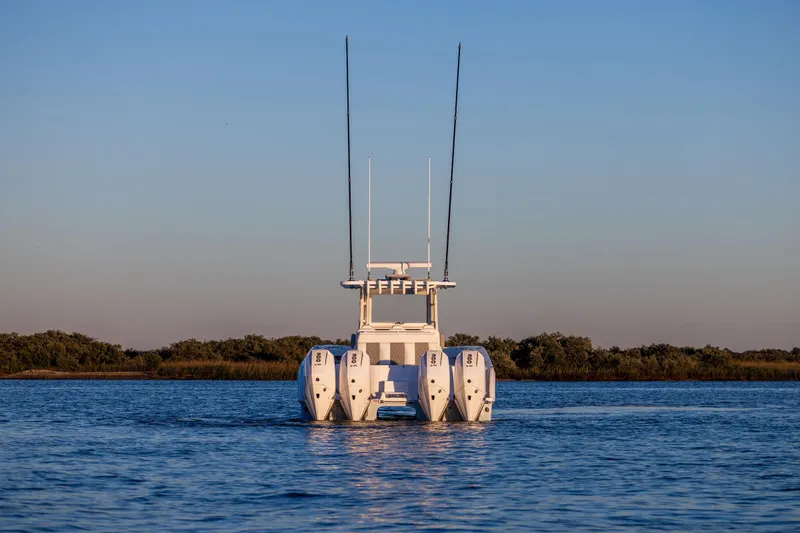 Slide: The Image of 2025 Invincible 38 Catamaran on calm water, rear view, showcasing powerful engines. - 6