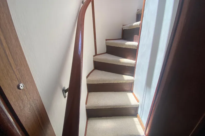 Slide: The Image of Carpeted stairs inside a 1990 Viking 63 Motor Yacht, featuring wooden handrails. - 33