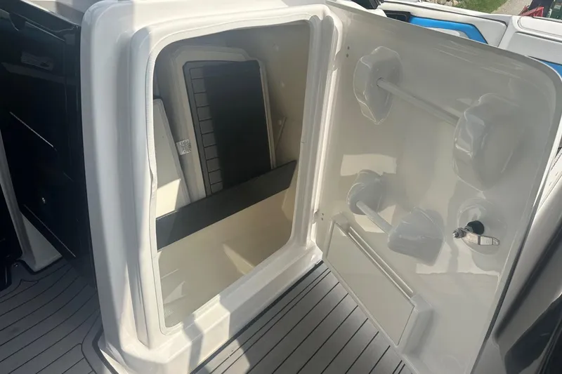 Slide: The Image of Storage compartment in a 2018 Yamaha 242 X boat, featuring interior shelving and secure latch. - 20