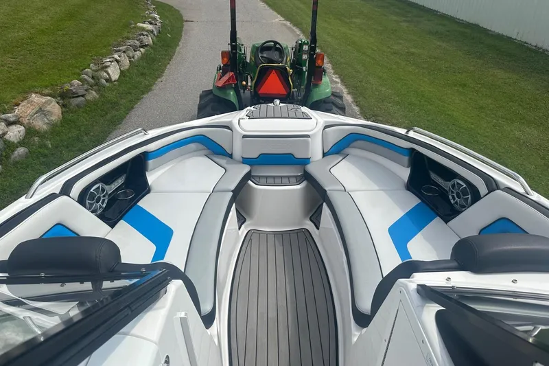 Slide: The Image of 2018 Yamaha 242 X boat interior with blue and white seating, parked on a driveway. - 21
