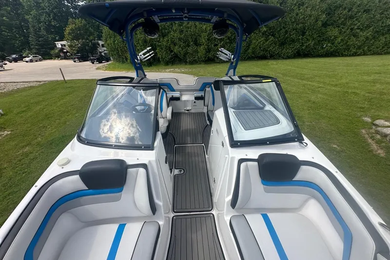 Slide: The Image of 2018 Yamaha 242 X boat interior with blue accents, parked on grass. - 25