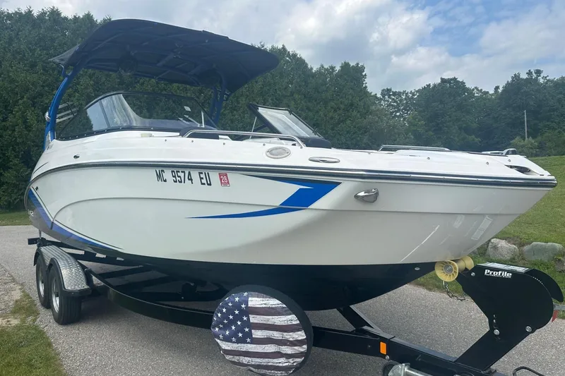 Slide: The Image of 2018 Yamaha 242 X boat on trailer, white with blue accents, parked outdoors. - 7